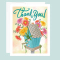 Greeting card with a blue birdhouse and flowers, featuring the text 'Thank You!' in hand drawn letters on a light blue background.