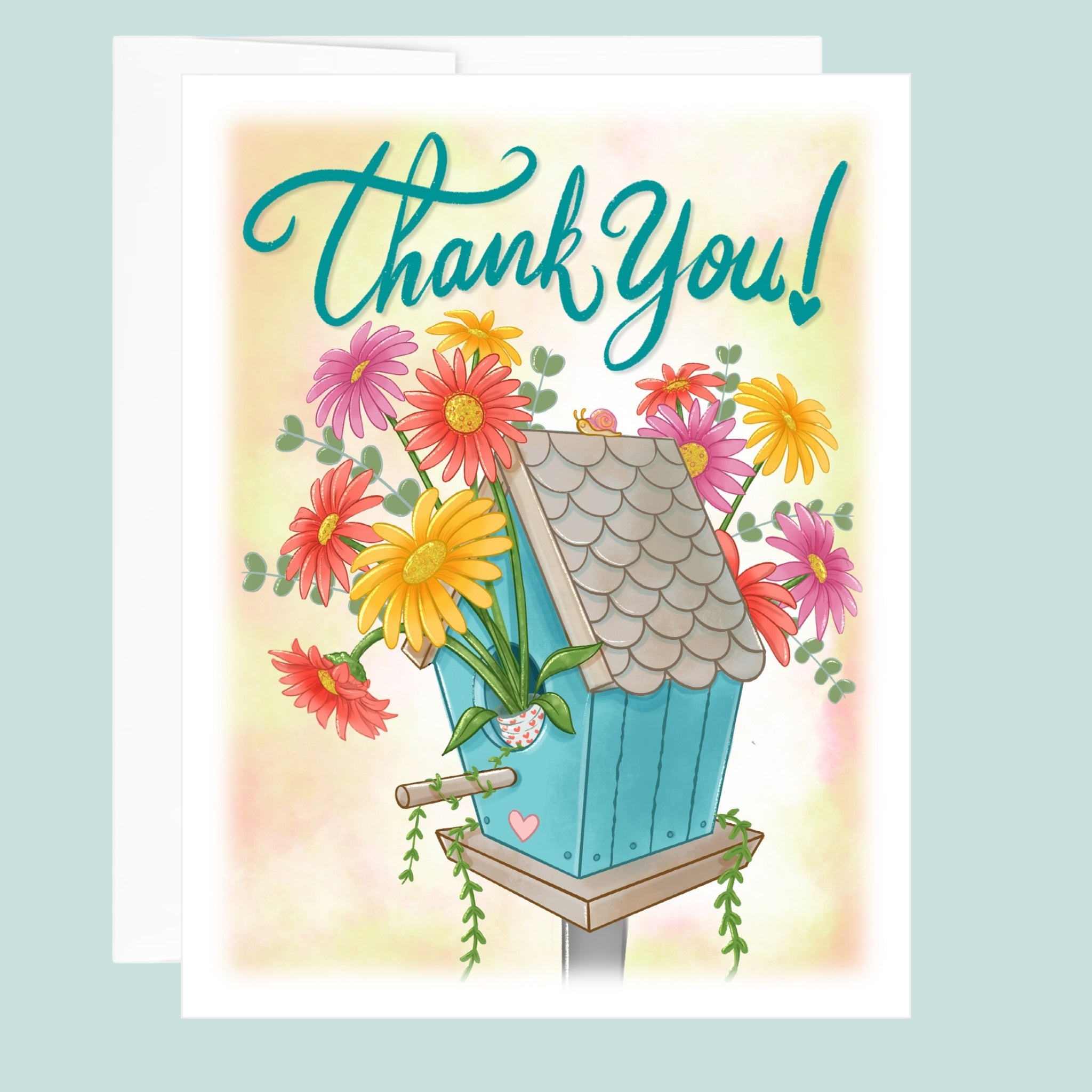Greeting card with a blue birdhouse and flowers, featuring the text 'Thank You!' in hand drawn letters on a light blue background.