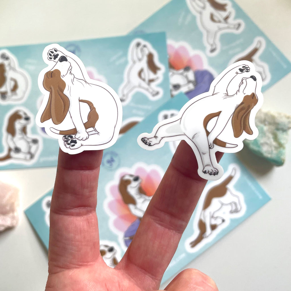 Hand holding a sticker of dogs in yoga poses with a blue background featuring more stickers.