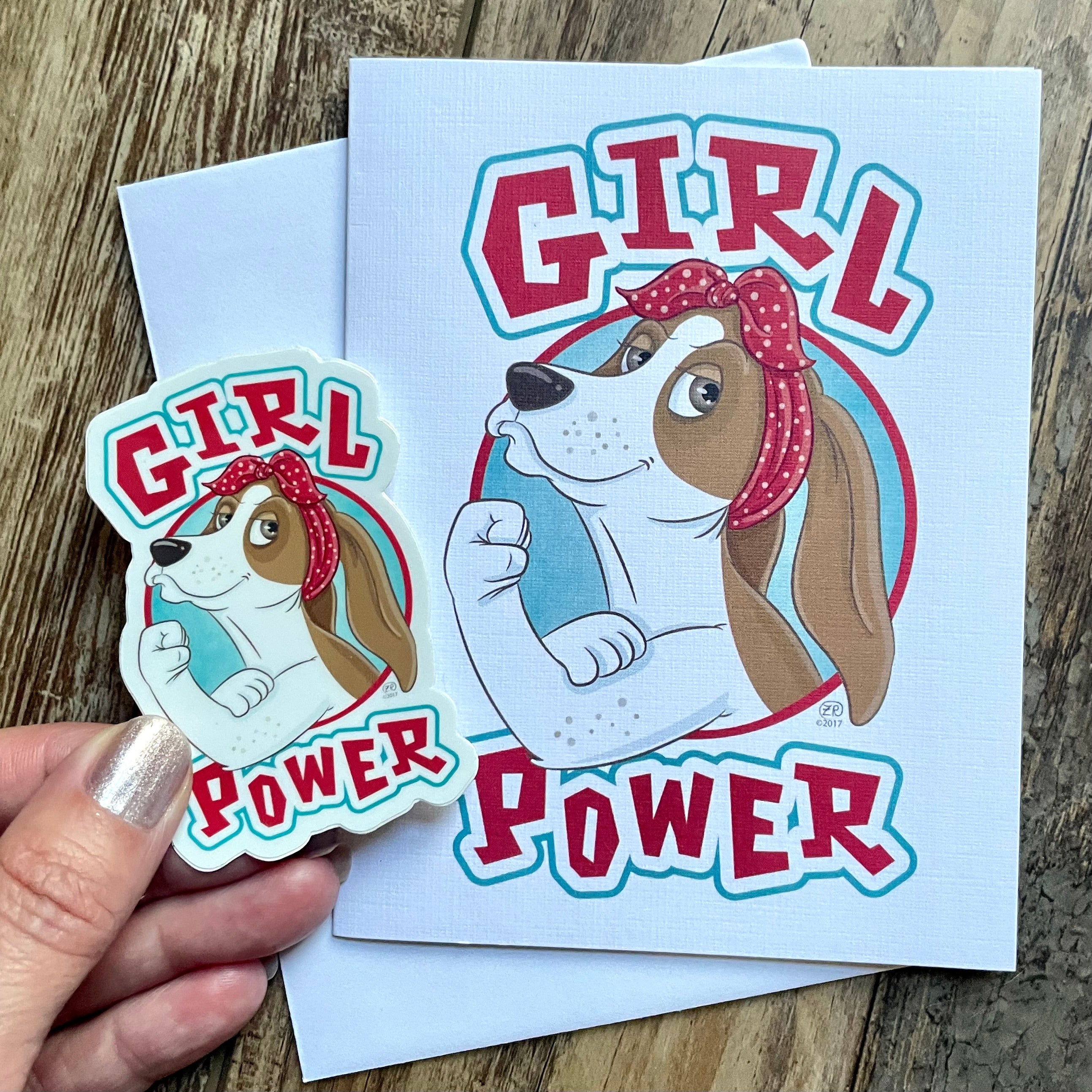 Sticker and card with 'Girl Power' design on a wooden surface