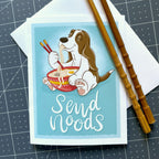 Card with a cartoon dog eating noodles and holding chopsticks, with text 'Send Noods' on a blue background.