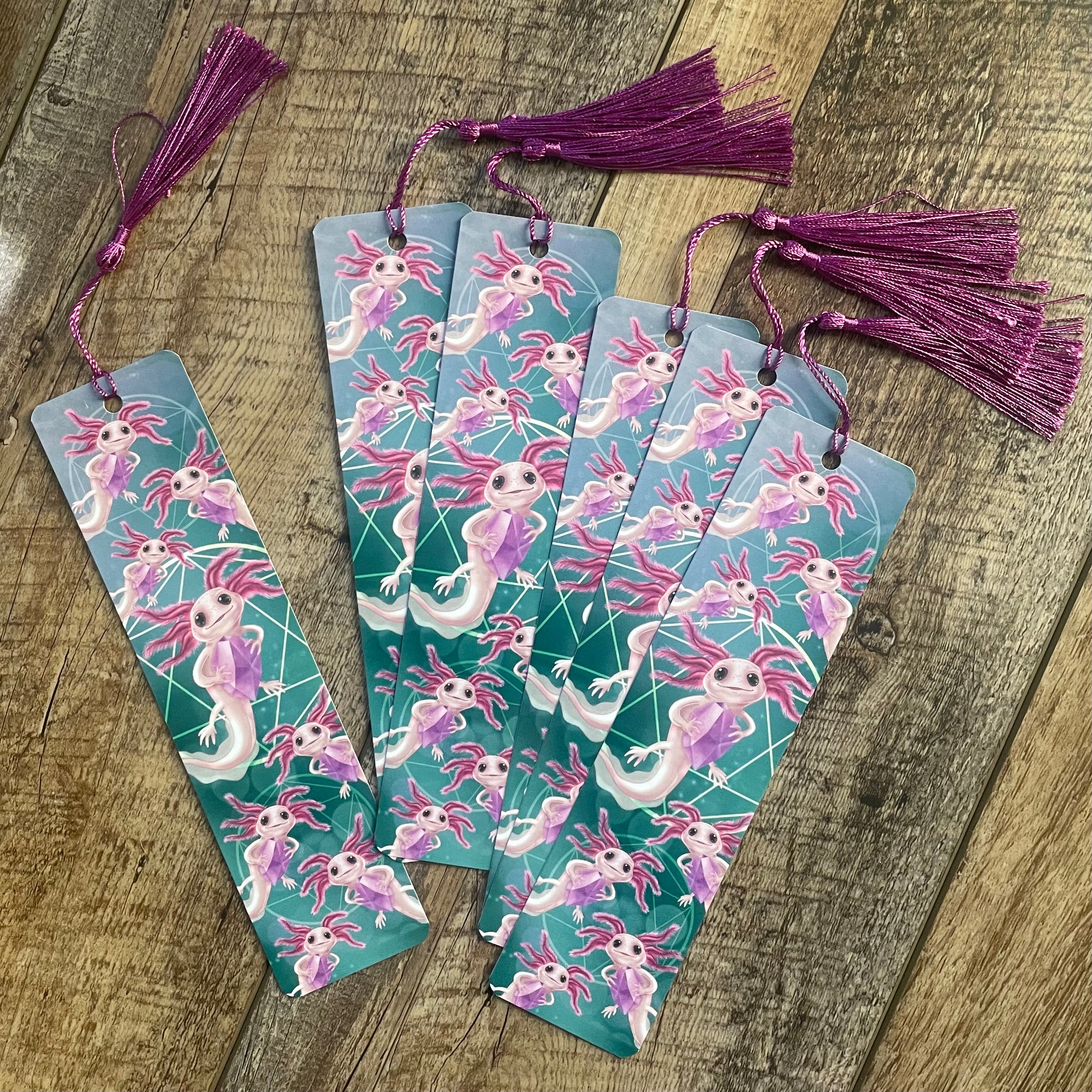 Set of bookmarks with axolotl design on a wooden surface