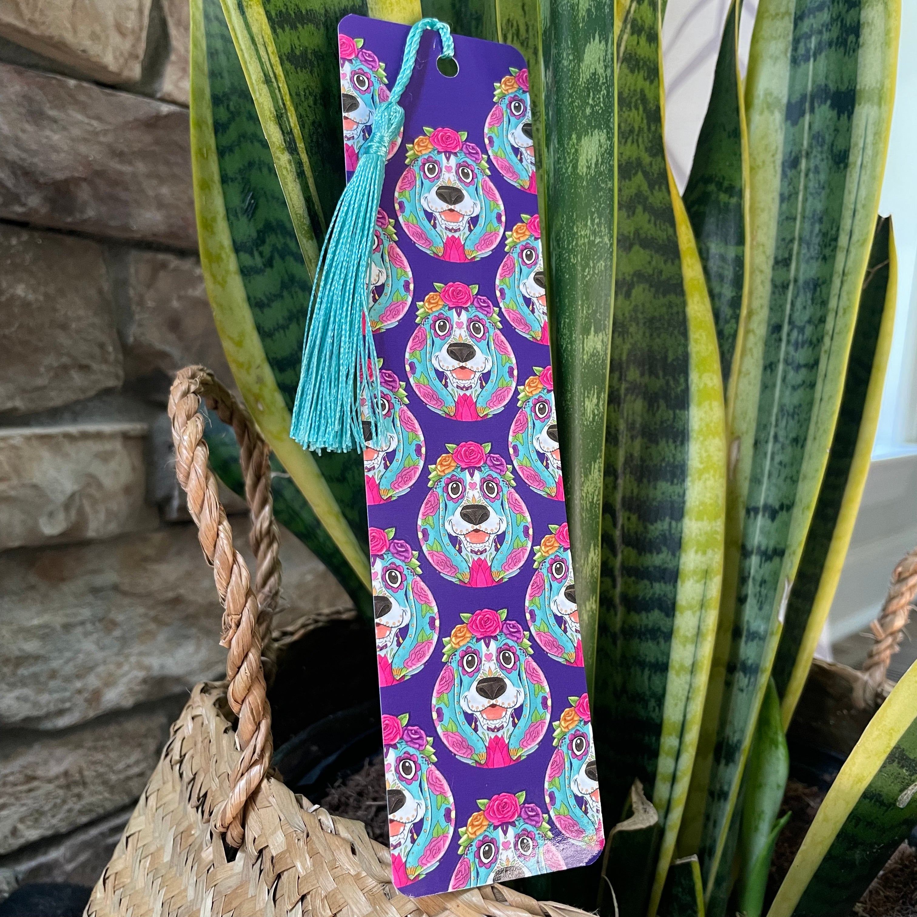 Colorful bookmark with dog design on a purple background, placed on a plant