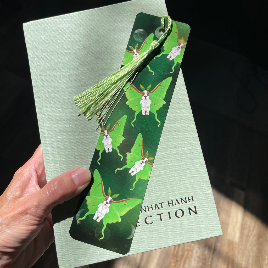 Hand holding a green bookmark with butterfly design on a book