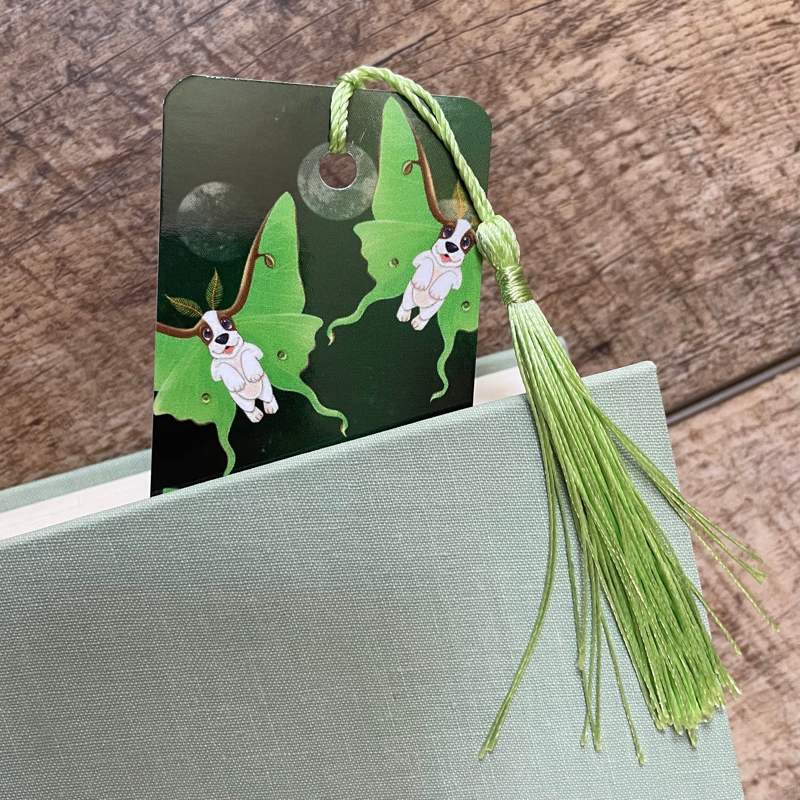 Green tassel bookmark with butterfly design on a wooden surface