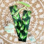 Green and black earrings with butterfly design on a textured surface