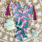 Two colorful bookmarks with axolotl designs on a textured surface with crystals.