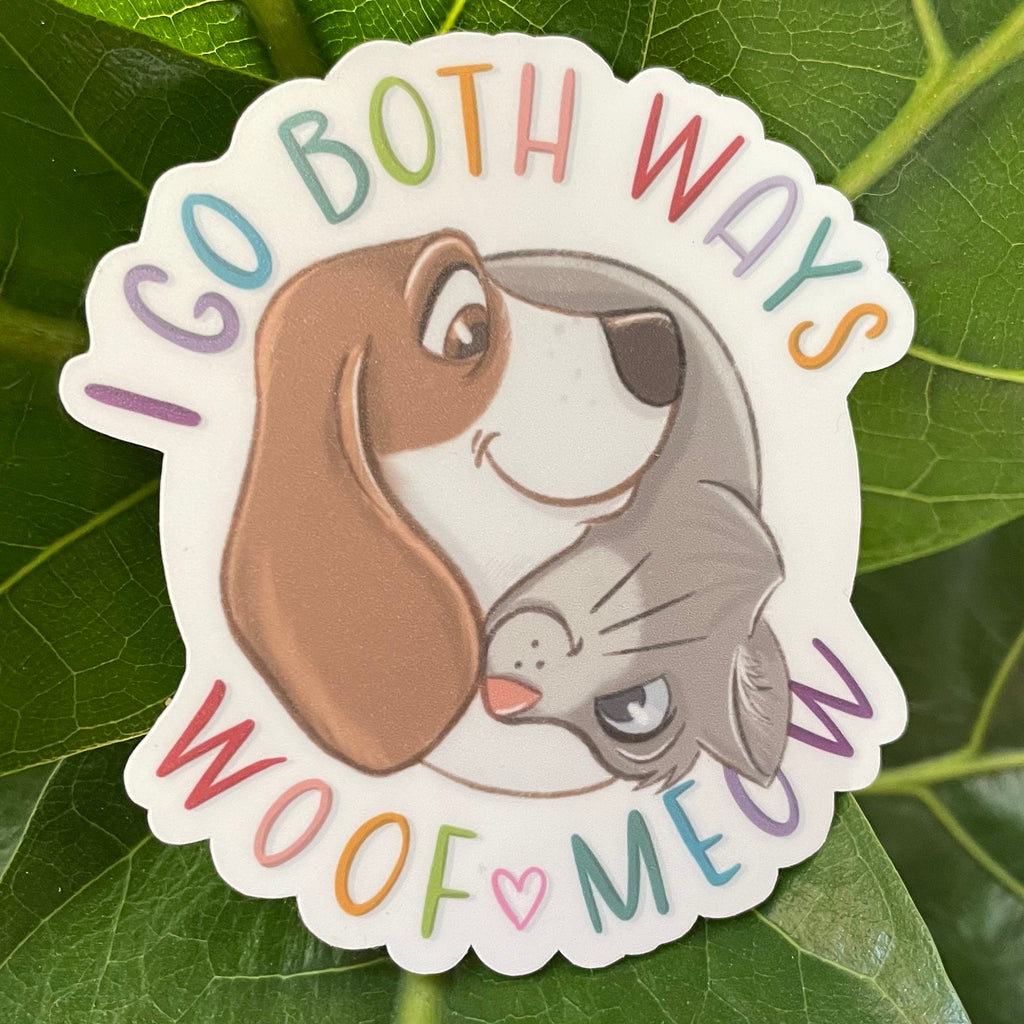 Sticker with a dog and cat hugging with text 'I go both ways, woof meow' on a leaf background