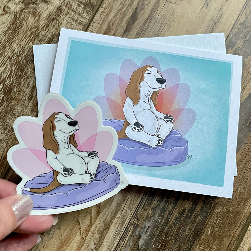 Cartoon dog sticker held over a printed card with a similar design on a wooden surface.