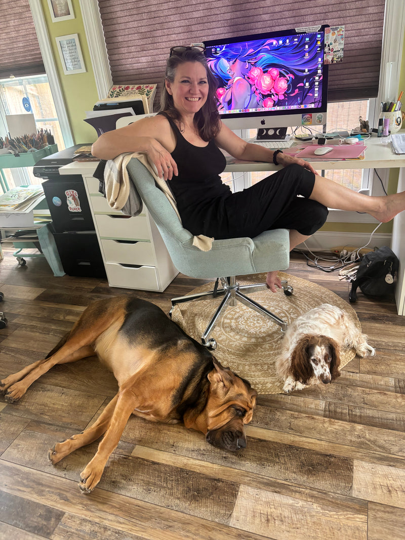 Zoe Ranucci sitting on a chair with two dogs on a wooden floor in a home setting.