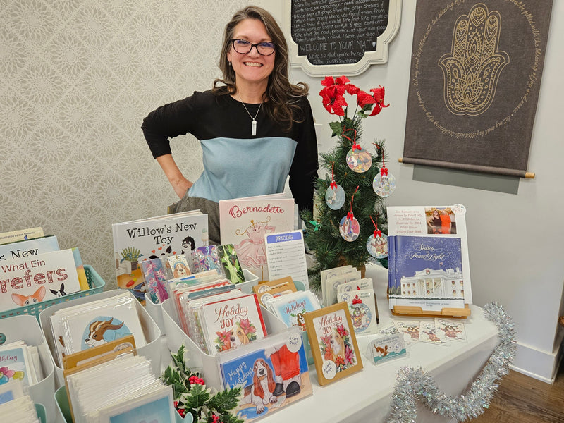 Zoe Ranucci standing behind a display of greeting cards with Christmas decorations in the background.