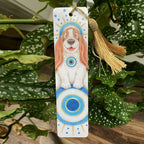 Bookmark with a dog illustration and decorative tassel on a leafy background